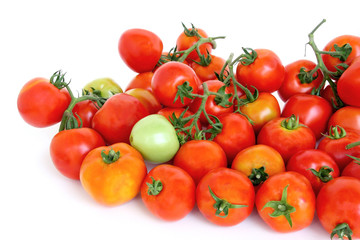 Group of red tomatoes with one green on white background.