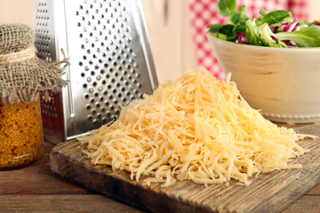 Grated cheese on wooden cutting board in kitchen