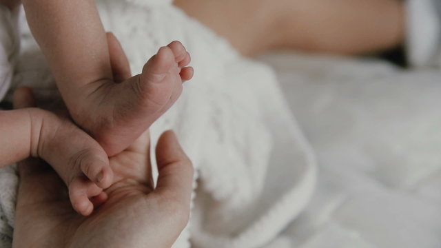 mother hold feets of newborn baby