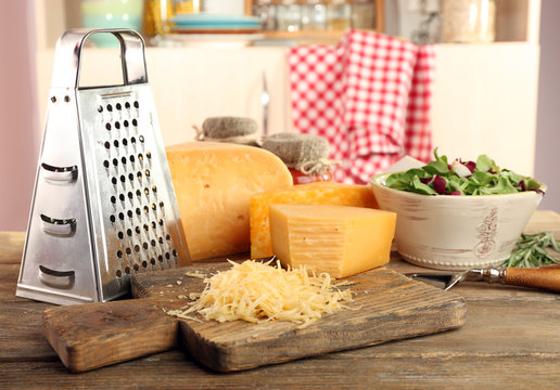 Grated cheese on wooden table on cutting board in kitchen
