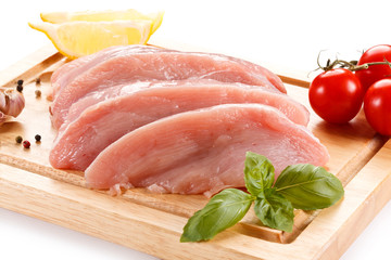 Raw chicken breasts on cutting board on white background
