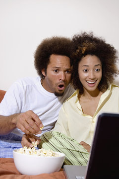 African couple watching movie on laptop