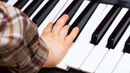 Obraz premium Close up of Keybord of synthetizer and child hands