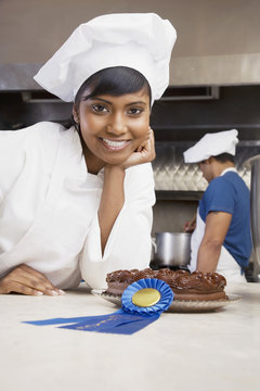 Mixed Race female pastry chef with blue ribbon and cake
