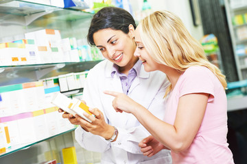Pharmacy chemist consulting woman in drugstore