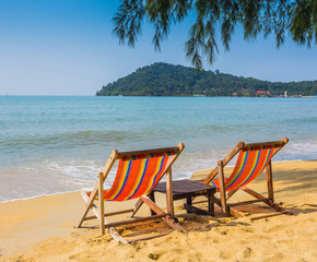 sun beach chairs on shore near sea.