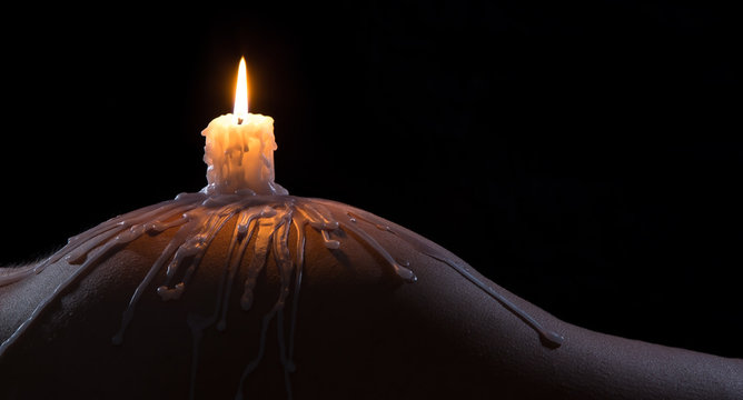 Body scape of a well-shaped woman with burning candle and wax on