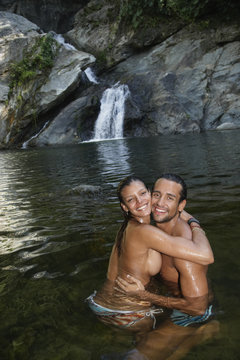 Topless Hispanic couple hugging in water