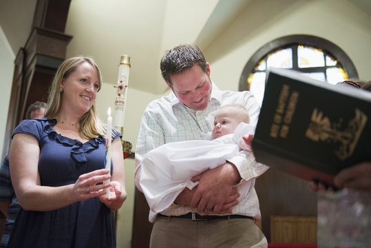 Caucasian parents having baby baptized in church