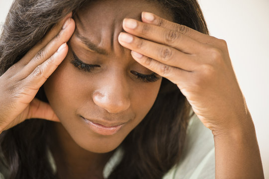 Black woman frowning with head in hands - Powered by Adobe