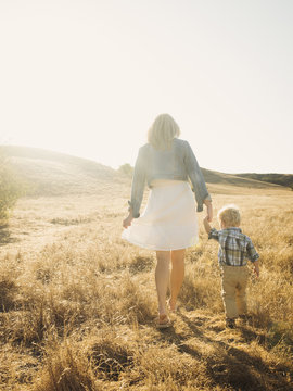 Caucasian mother and son walking in rural field