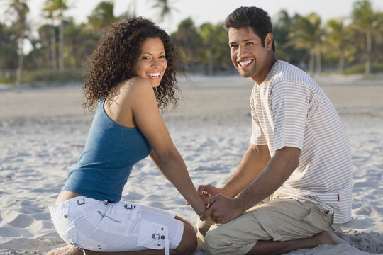 Hispanic couple holding hands at beach
