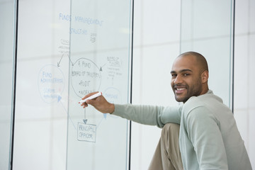 African businessman writing on clear dry erase board