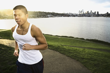 Asian man jogging along urban waterfront