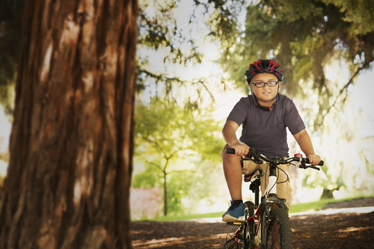 Mixed race boy riding mountain bike in forest