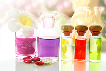 Bottles of natural aroma oil on flowers background