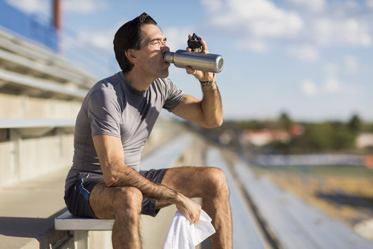 Hispanic athlete resting on bleachers