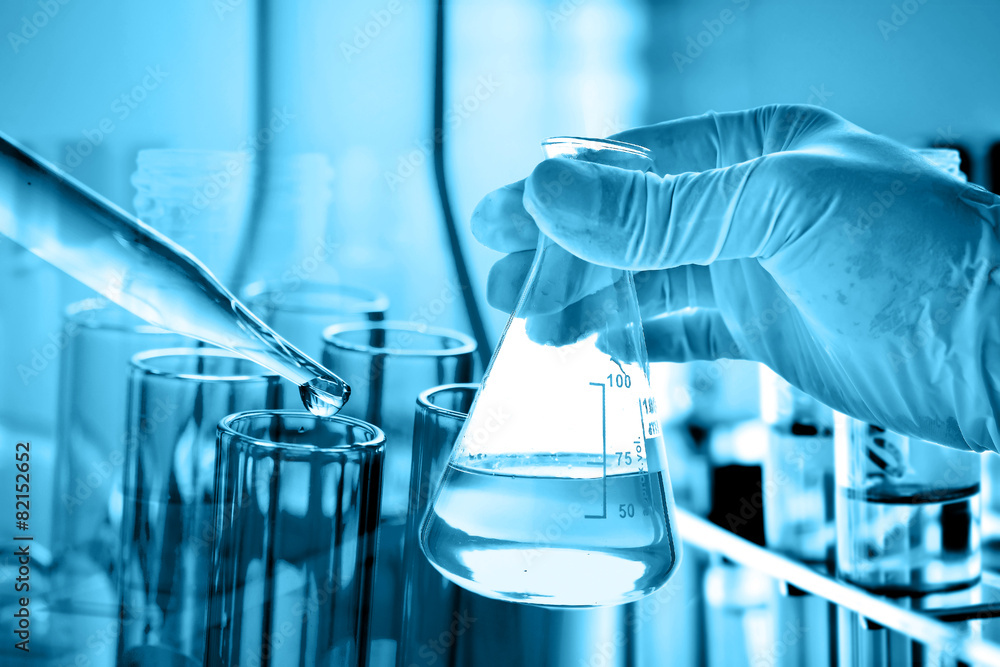 Wall mural flask in scientist hand with lab glassware background