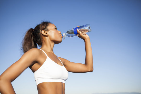 Mixed race woman drinking water bottle