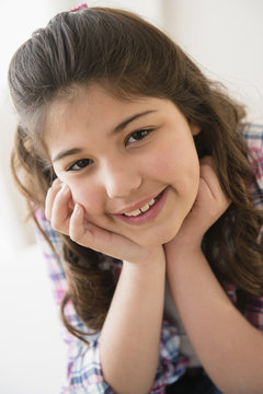 Hispanic girl smiling with chin in hands