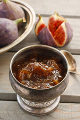 Bowl of fig jam and raw figs on rustic wooden table