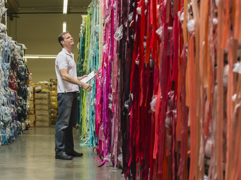 Caucasian worker examining fabric in textile factory
