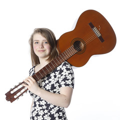 Fototapeta premium teenage girl in dress holds guitar on shoulder in studio
