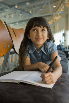 Hispanic girl writing in diary in airport