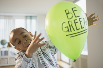 African American boy playing with ,'be green' balloon