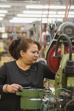 Hispanic worker operating machinery in textile factory
