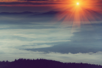 Majestic sunrise in the foggy mountain layers landscape.