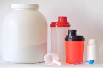 Big jar of protein powder, bottles and two shakers