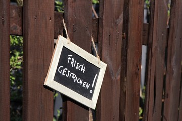 Kreidetafel an einem frisch lasierten Gartenzaun