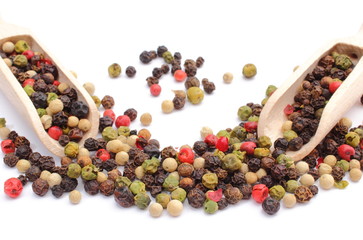 Colored pepper on wooden spoon. White background