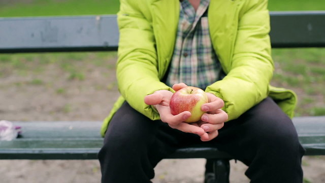 Man showing ripe and tasty apple to the camera in the park