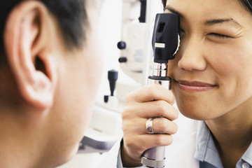 Asian female optometrist examining patient