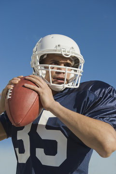 Hispanic male football player throwing ball