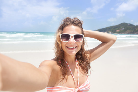 Beautiful young woman doing selfie on the beach - Powered by Adobe