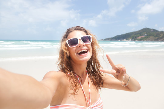 Beautiful young woman doing selfie on the beach