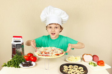 Young smiling chef shows how to cook a pizza