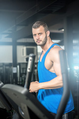 Obraz na płótnie Canvas Young man running at treadmill in gym