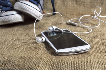 Smart phone on a table cloth with sneakers.