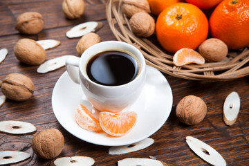 Cup of coffee with tangerines and walnut