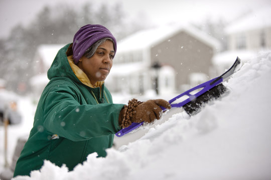 African American Woman Scraping Snow From Windshield