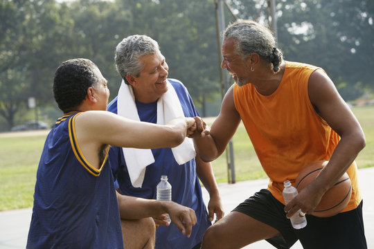 Multi-ethnic men laughing on basketball court