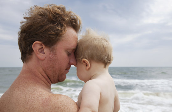 Father holding baby on beach