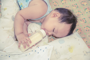 Cute Asian baby boy sleeping and drinking milk