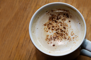 coffee with milk foam and cocoa on a wooden table, copy space