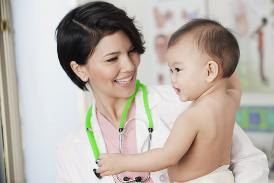 Doctor holding smiling baby in doctor's office
