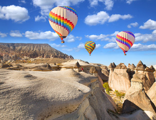 Plakaty  Balon na ogrzane powietrze latający nad skalnym krajobrazem w Kapadocji, Turcja.